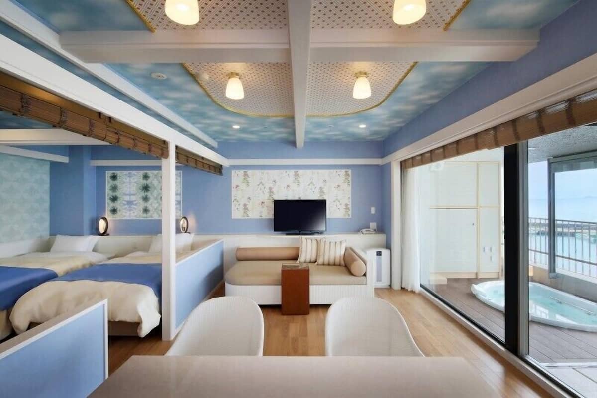 A modern interior with a sofa, a TV, and a balcony with a hot tub.