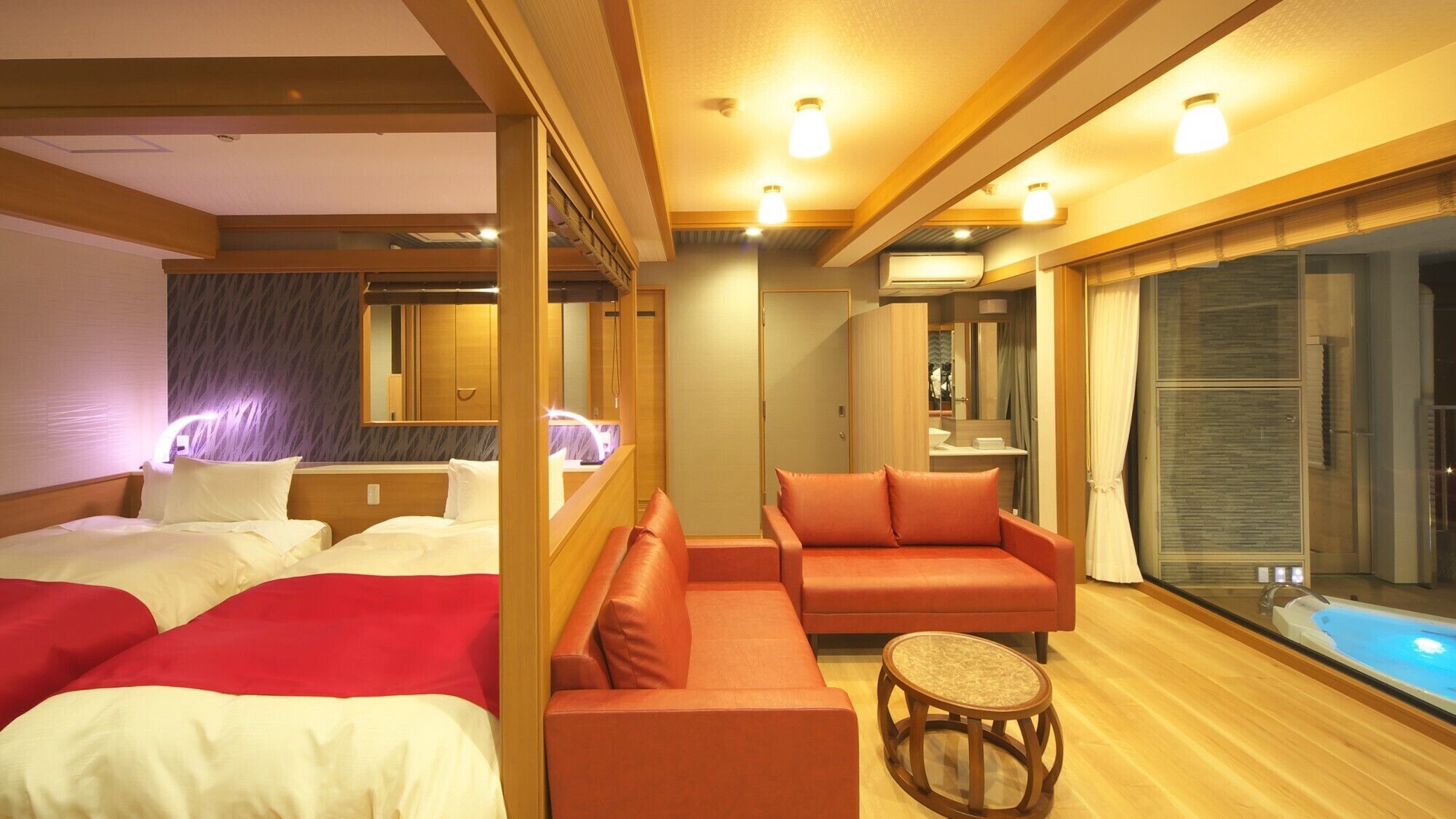 A hotel room with two beds, a sofa, a small round table, and a large window.