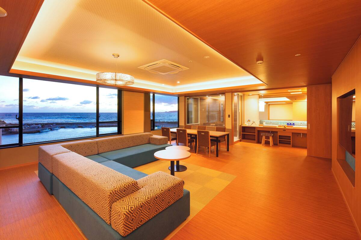 A modern interior with a large seating area, a dining table, and a kitchen area.
