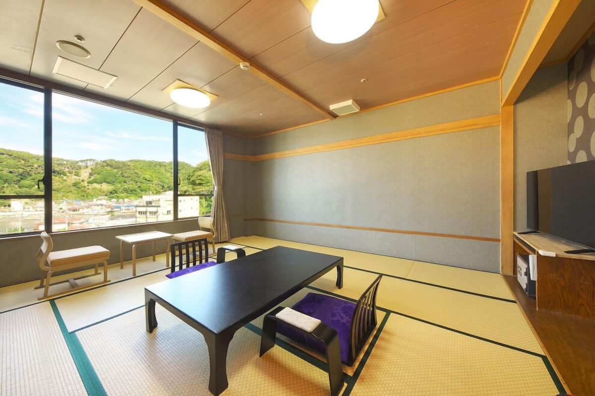 A room with tatami mats, a black table, a sofa, and a TV.