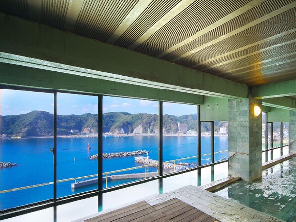 Una amplia piscina interior con vistas a la costa y montañas.