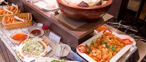 Un buffet proposant divers plats, notamment des salades, des amuse-gueules et un grand saladier de fromage râpé.