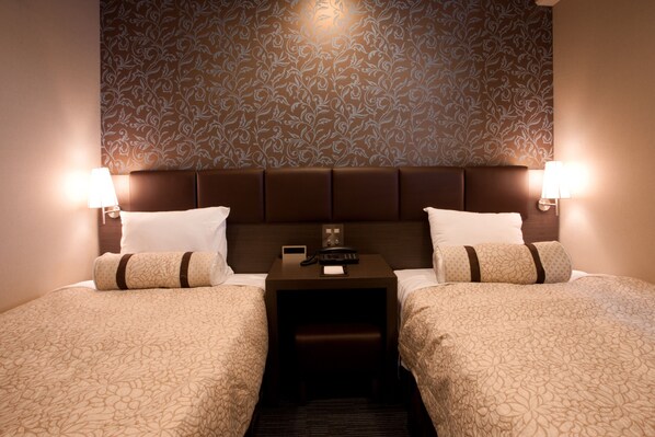 A hotel room with two beds, a nightstand between them, and a patterned wallpaper.