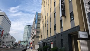 A modern building with multiple floors, featuring a prominent sign for a hotel. - Kuretake Inn Premium Shizuokaekimae (Shizuoka)