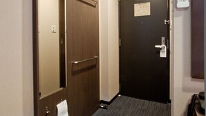 A hotel hallway with a carpeted floor, a door with a mirror, a towel hanging on the door, and a telephone on the wall. - Kuretake Inn Premium Shizuokaekimae (Shizuoka)
