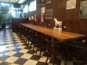En bardisk med en lång träbänk, flera barstolar och en vit häststaty med texten ”WHITE HORSE SCOTCH WHISKY”.