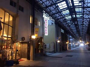 En överbyggd gångväg med en skylt för restaurangen ”Mishisahi”, krukväxter och en cykel.