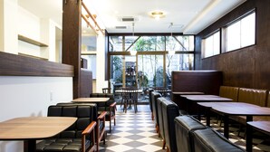 Un interior de restaurante con piso a cuadros, mesas de madera y asientos de cuero negro.