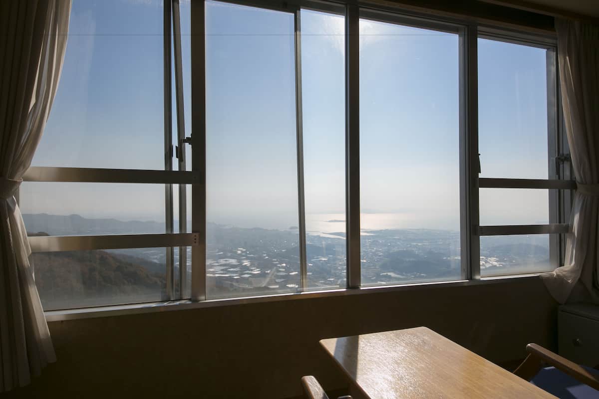 A room with a large window offering a view of a cityscape and mountains.