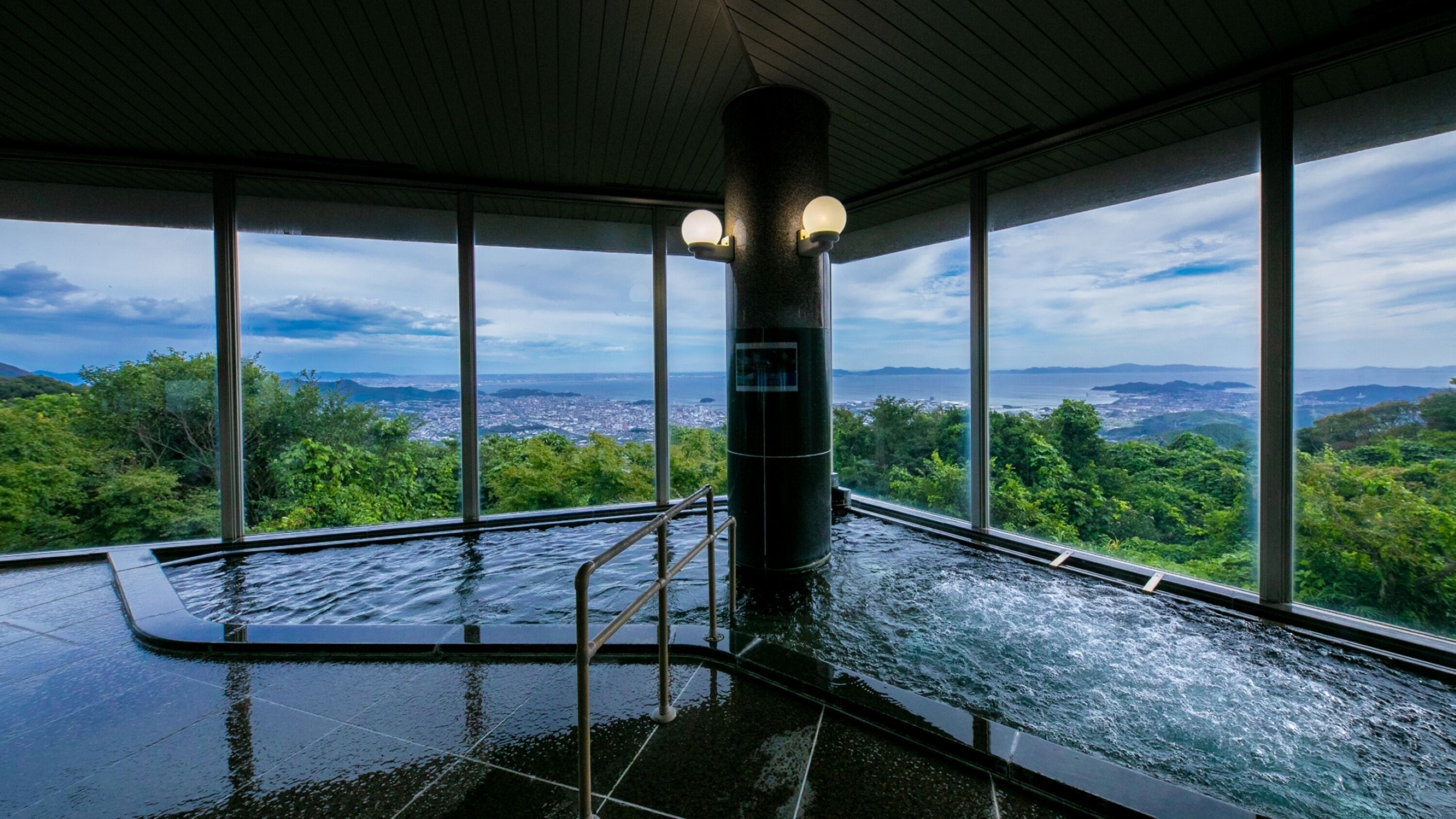 A hot tub with a view of a city and mountains.