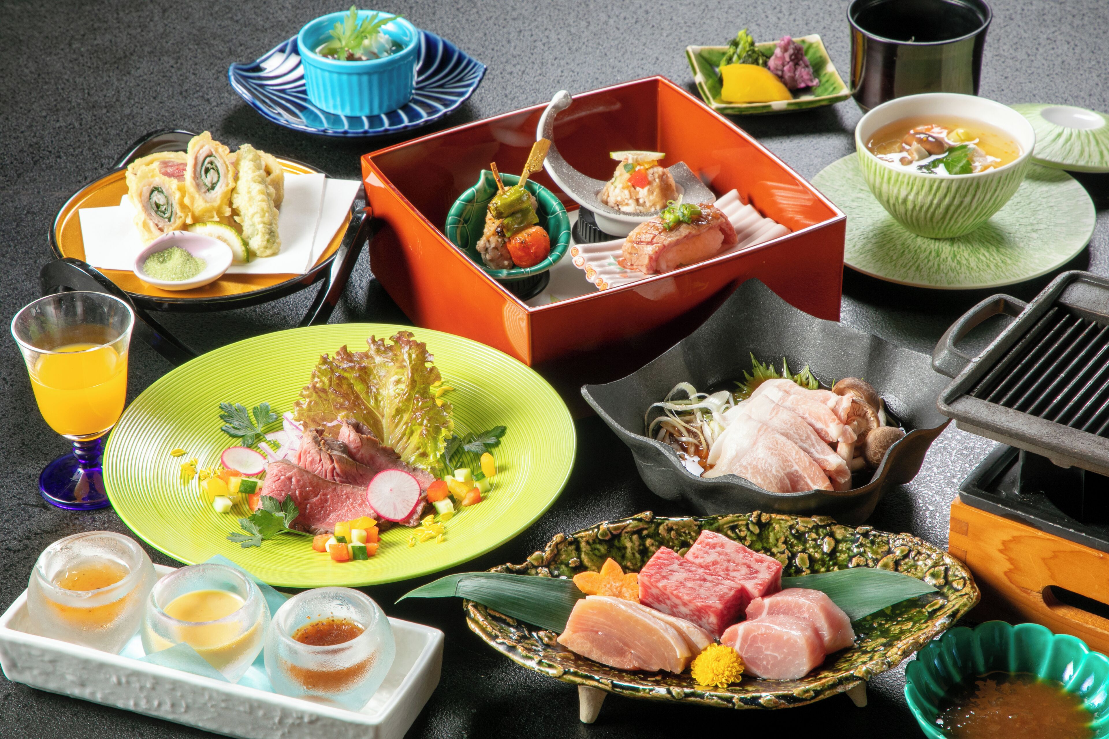 Une variété de plats et de condiments sont disposés sur une table, notamment des sushis, des sashimis et un bol de soupe.