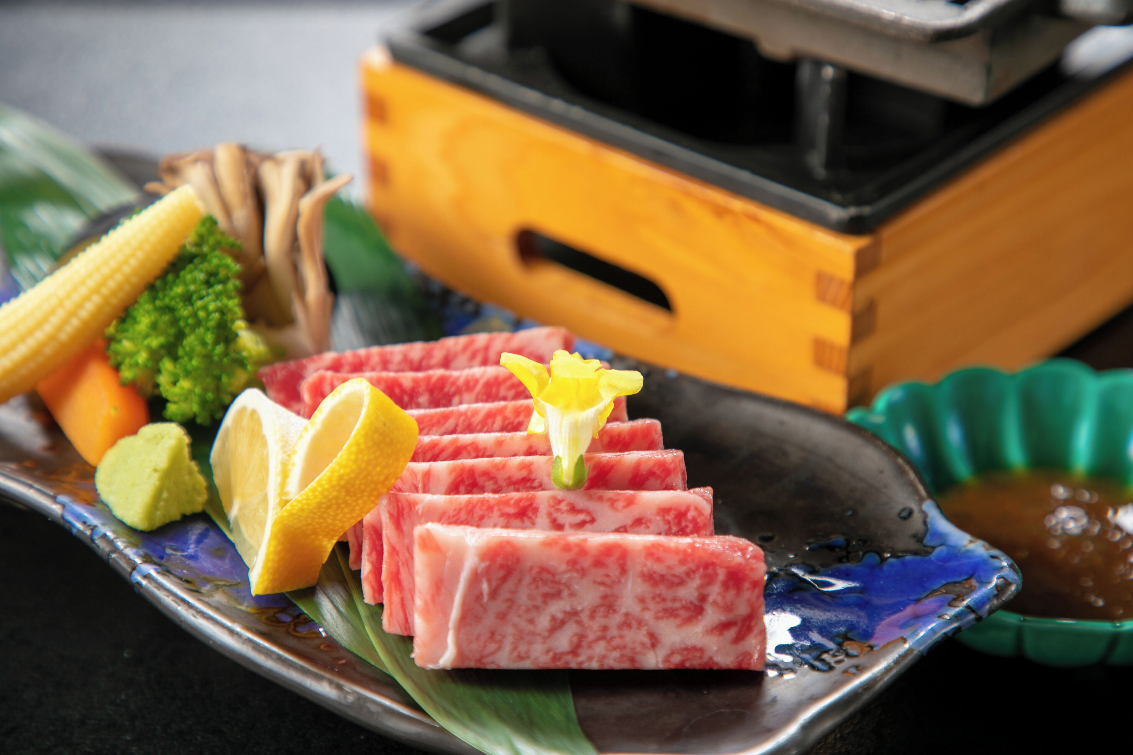 A plate with sliced meat, vegetables, and a lemon wedge.