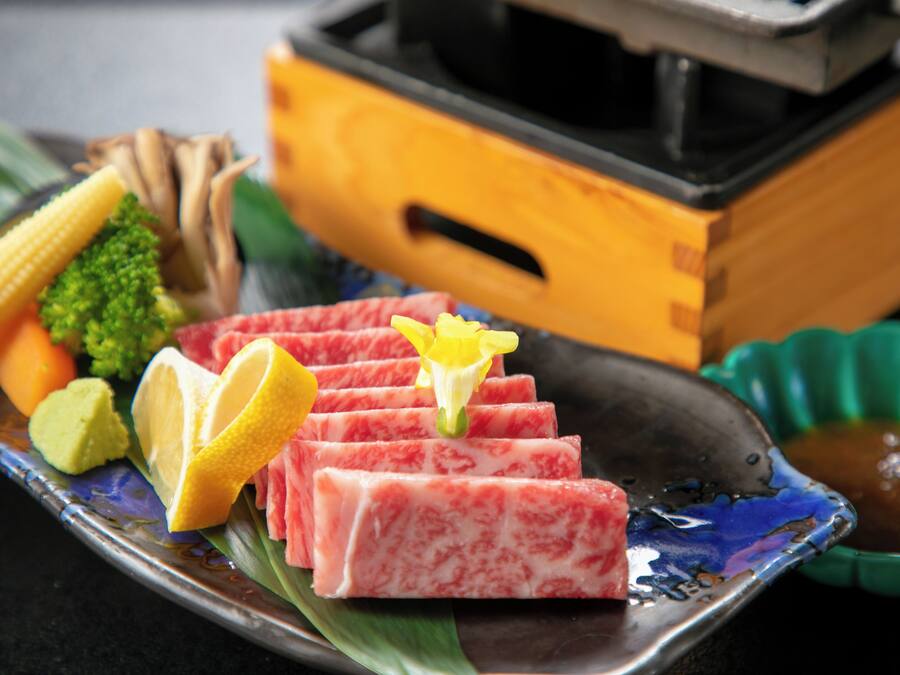 A plate with sliced meat, vegetables, and a lemon wedge.