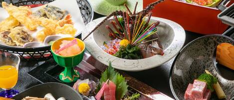 Diversidad de platos japoneses, como tempura, sashimi y preparaciones a la parrilla, presentados en una mesa con múltiples cuencos y fuentes.