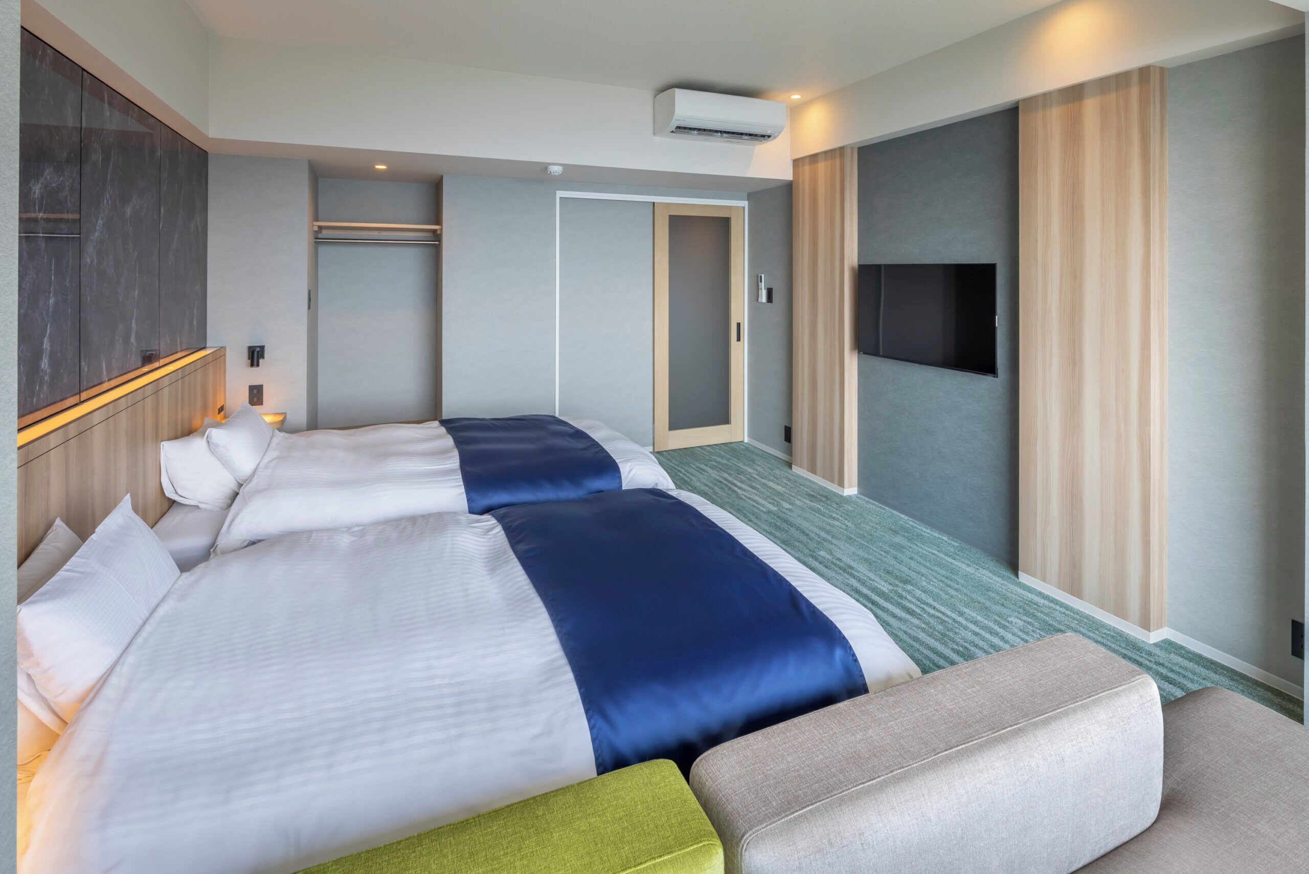 Ein Hotelzimmer mit zwei Betten, einem Schlafsofa, einem Fernseher und einem Kleiderschrank.