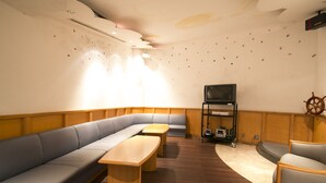 A cozy room with a curved wooden floor, a grey sofa, a wooden table, and a television on a stand.