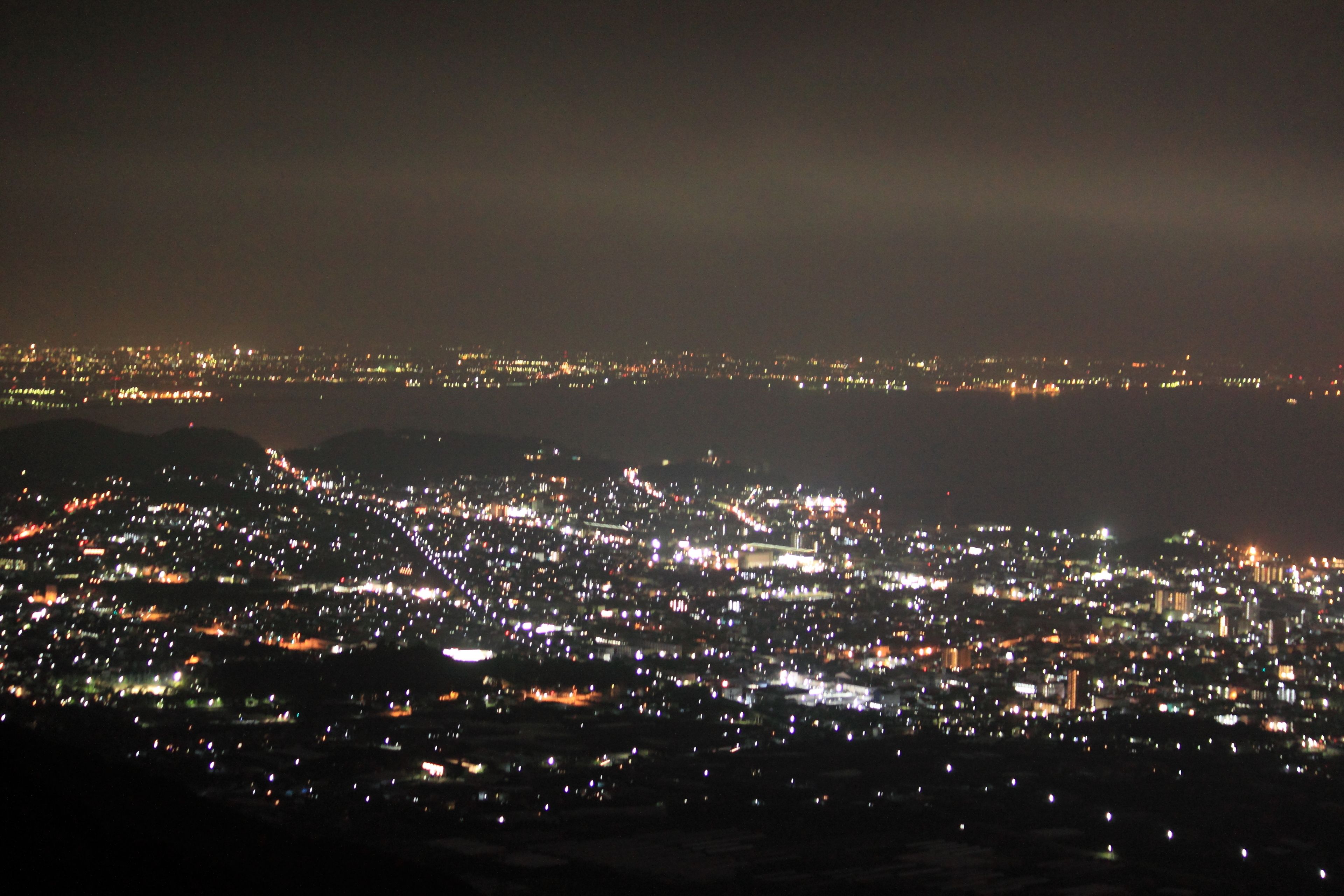 Un paisaje urbano nocturno con una gran concentración de luces, lo que indica una zona urbana activa.