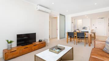 A modern living room with a flat-screen TV, wooden entertainment unit, and a coffee table.