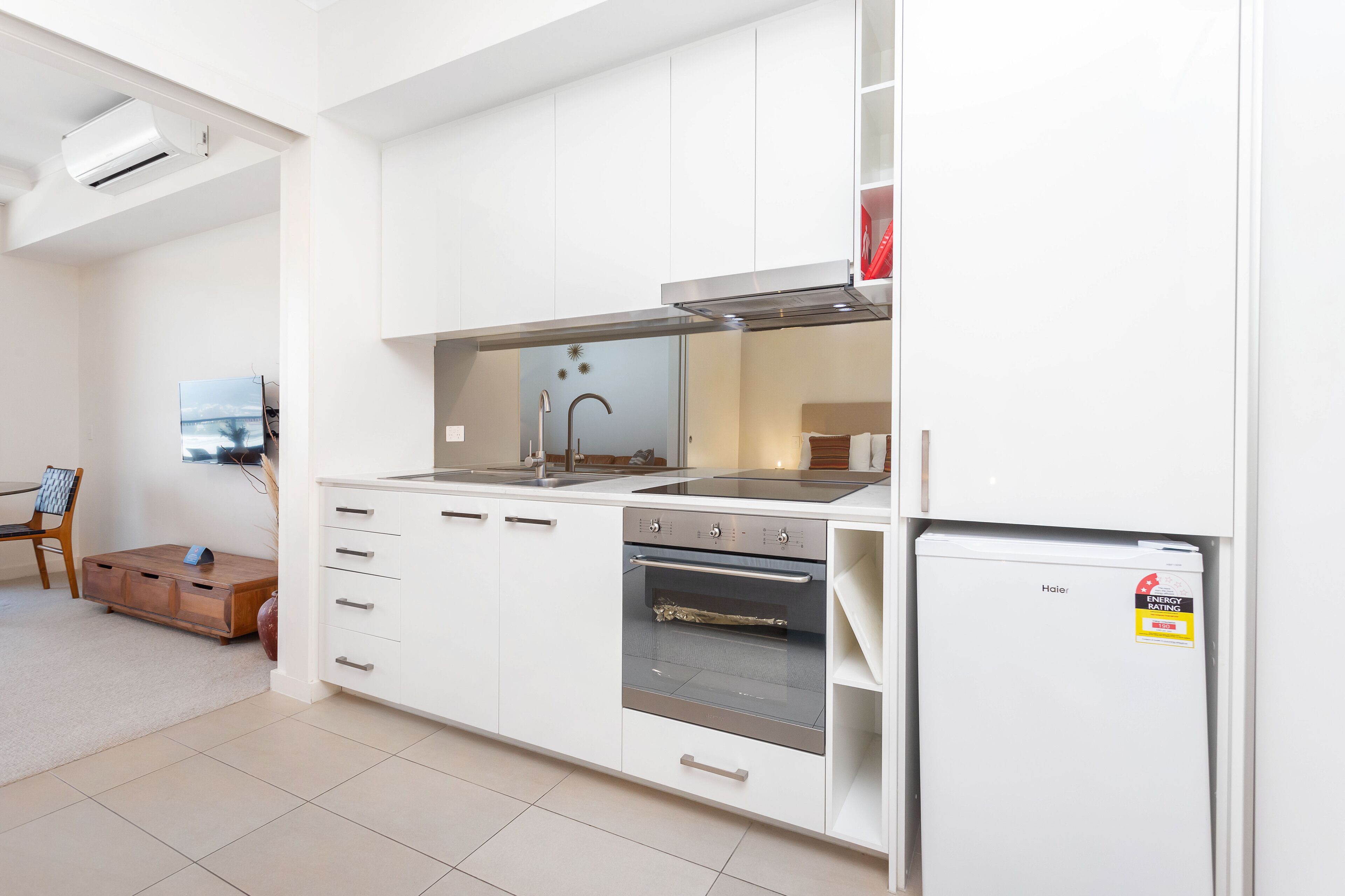 A modern kitchen with white cabinetry, a built-in oven, and a refrigerator.
