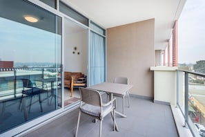 A balcony with a table and chairs, a sofa, and a view of a cityscape.