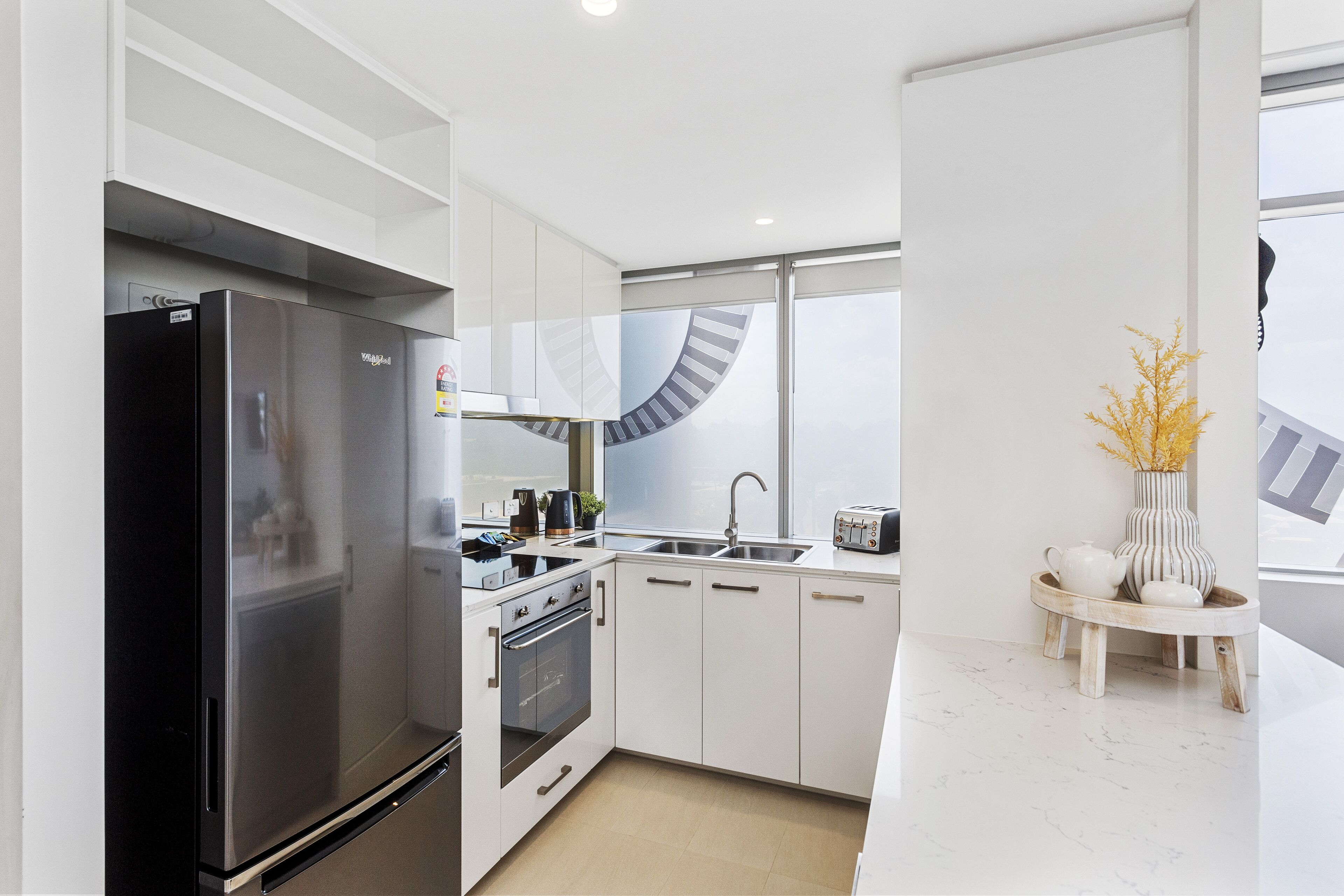 Una cocina moderna con refrigerador de acero inoxidable, horno empotrado y un lavamanos.