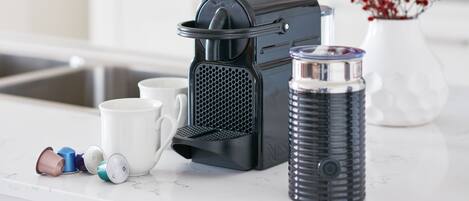 A kitchen with a coffee maker, a water dispenser, and a vase with red flowers on the counter.