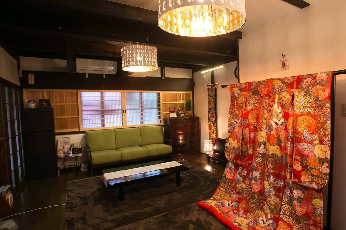 A traditional Japanese-style living room with a green sofa, a wooden coffee table, and a colorful tapestry.