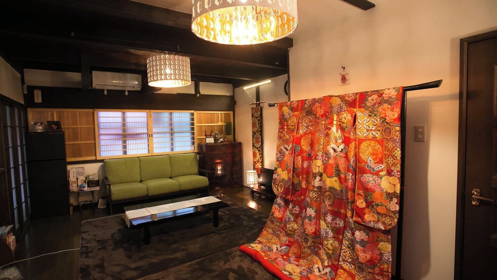 A traditional Japanese room with tatami flooring, a green sofa, a low table, and a colorful shoji screen.