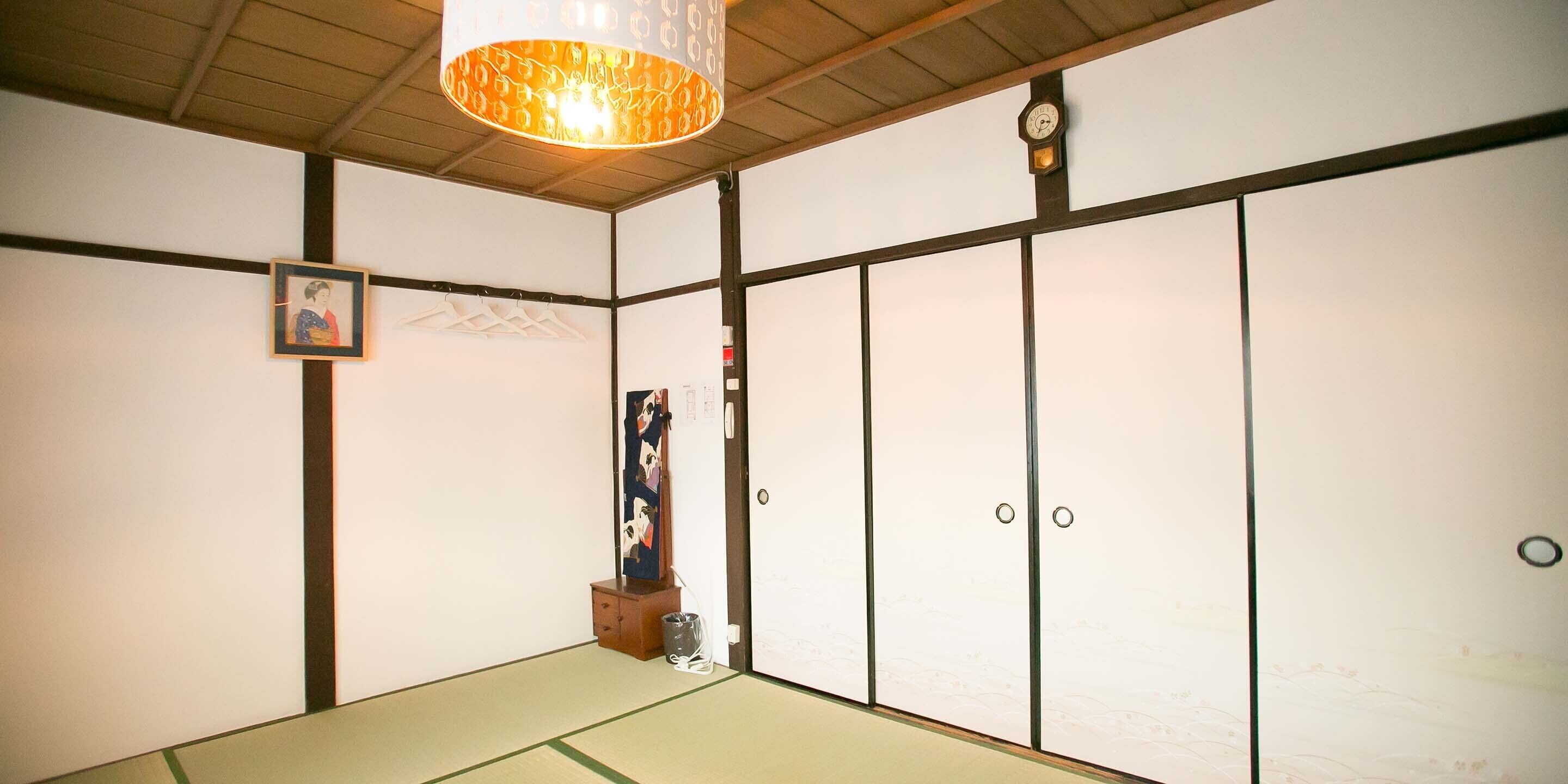 A traditional Japanese room with tatami flooring, shoji screens, and a hanging lamp.