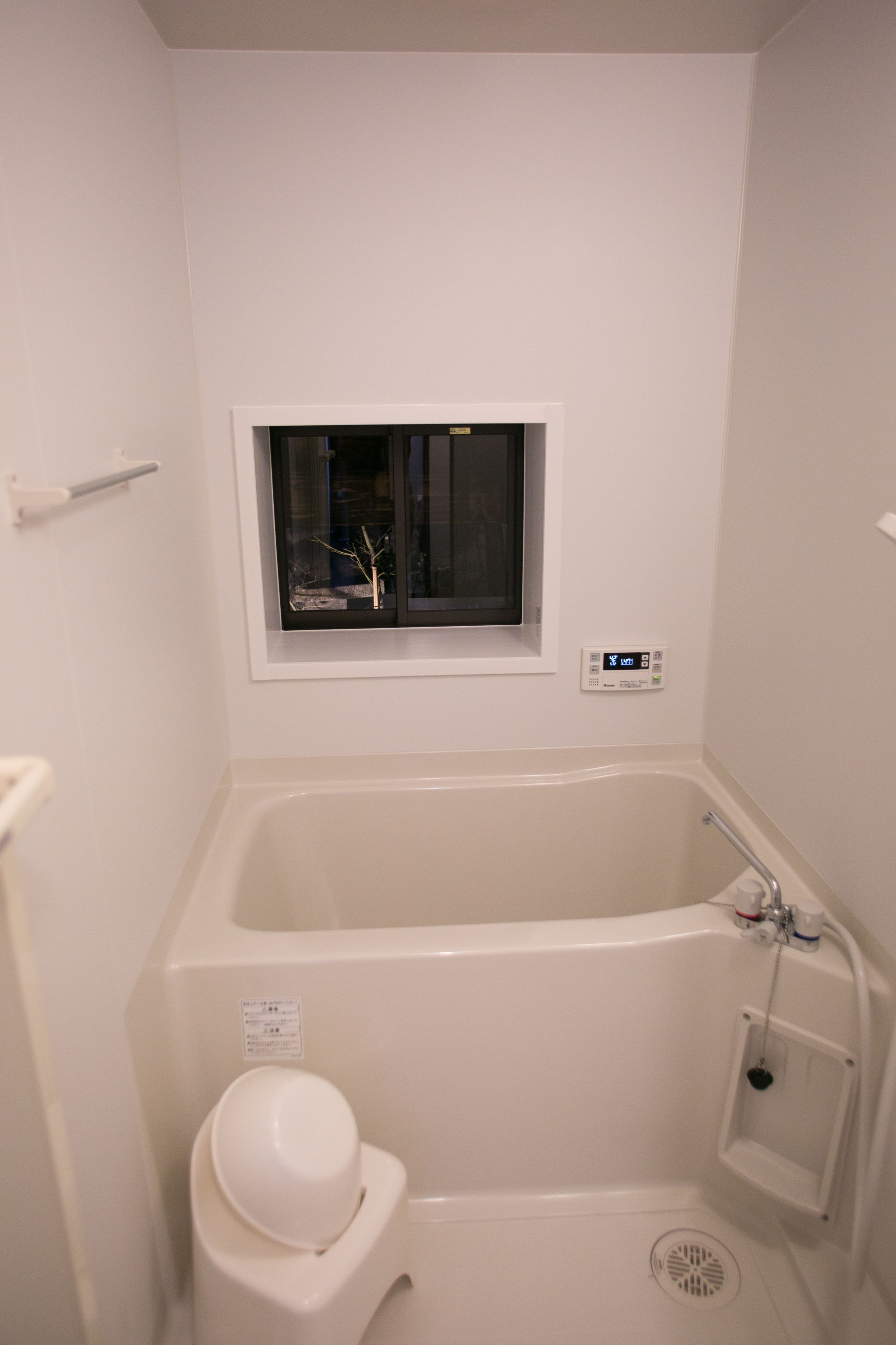Ein kleines, weißes Badezimmer mit Badewanne, Fenster und Toilette.