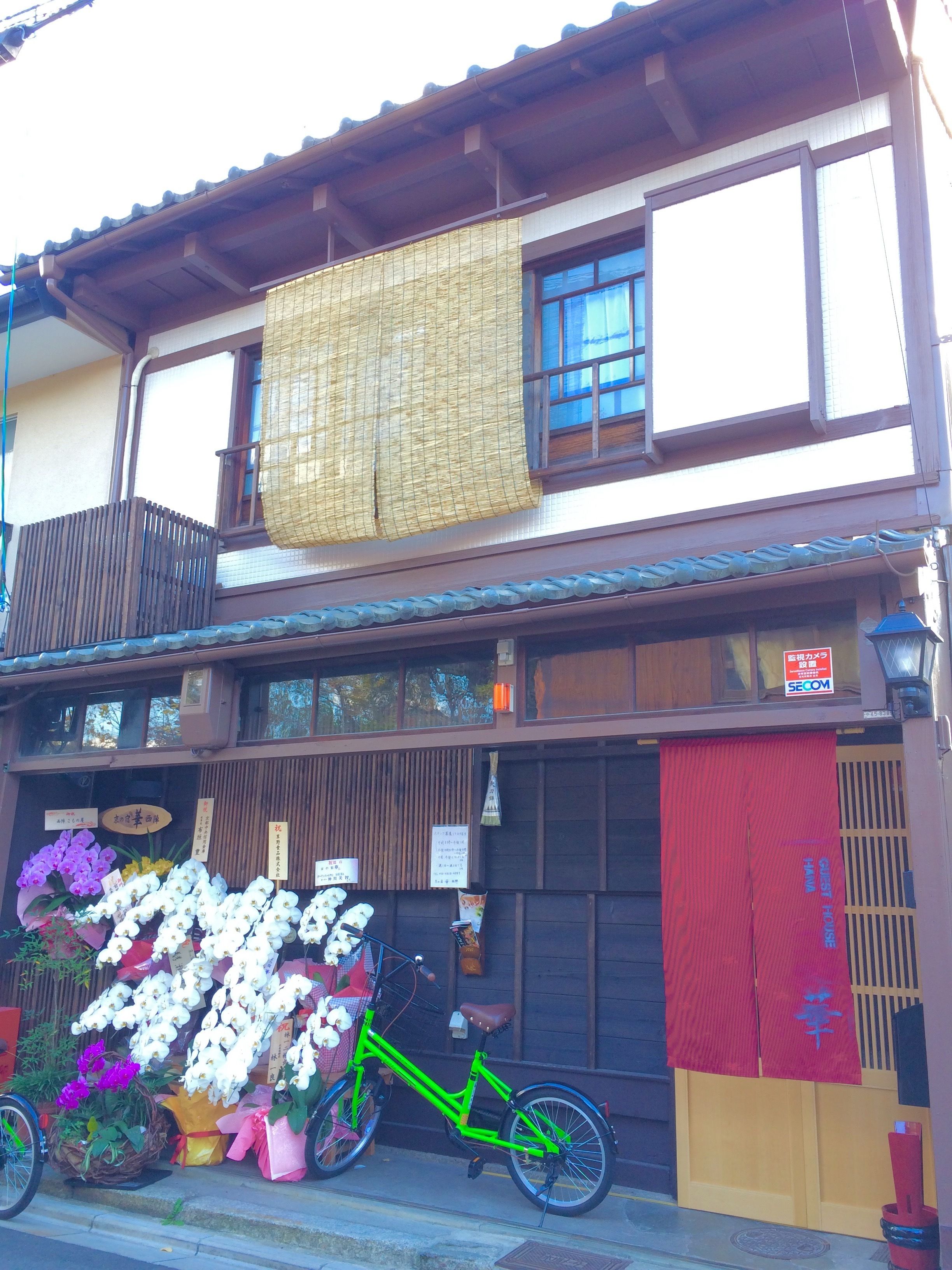 Een traditioneel Japans gebouw met balkon, een fiets en verschillende bloemen voor buiten.