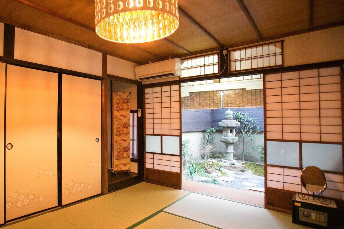A traditional Japanese room with tatami flooring, sliding doors, and a view of a garden.