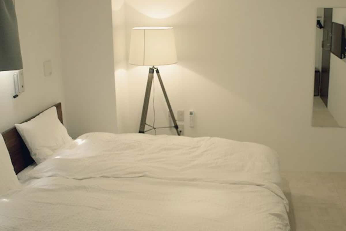 A hotel room with a bed, a lamp, a mirror, and a television.