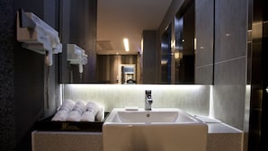 A hotel bathroom with a sink, towel dispenser, and a mirror. - W Hotel (Incheon)