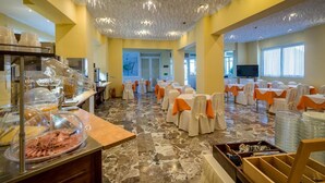 A banquet hall with tables set for events, a buffet area with food, and a television screen. - Lorenzo House Apartments (Kefalonia)