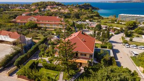 An aerial view of a coastal residential area with houses, a road, and a view of the sea. - Lorenzo House Apartments (Kefalonia)