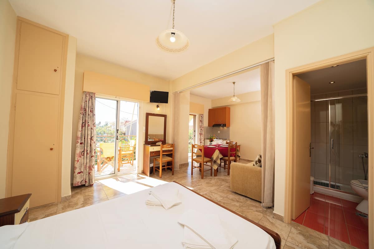 A hotel room with a bed, a dining area, a kitchen, and a bathroom.