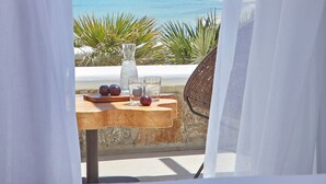 Ein Balkon mit Tisch für zwei Personen, mit Blick auf ein Küstendorf mit weißen Häusern und blauem Meer.