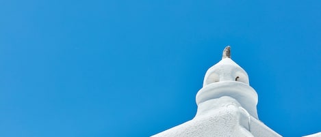 A white building with a dome and a spire against a clear blue sky.