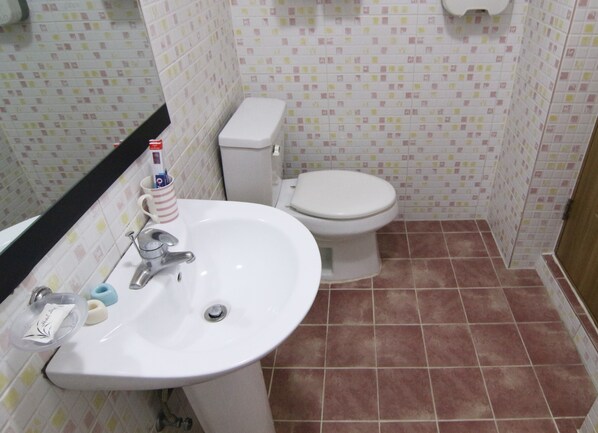 A bathroom with a white sink, toilet, and tiled walls.
