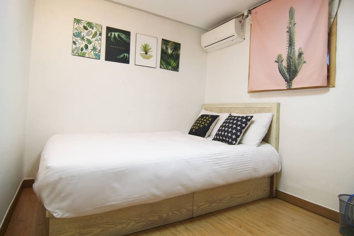 Una cama individual con estructura de madera y colchón blanco en una habitación con piso de madera.