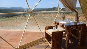 A wooden table with a vase and glasses, set against a view of a hilly landscape through a geodesic dome structure. - Azienda Agricola Pietra Serena B&B (Civitella Paganico)