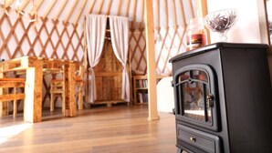 A cozy interior with a wooden dining table and chairs, a black stove, and a lattice wall. - Azienda Agricola Pietra Serena B&B (Civitella Paganico)