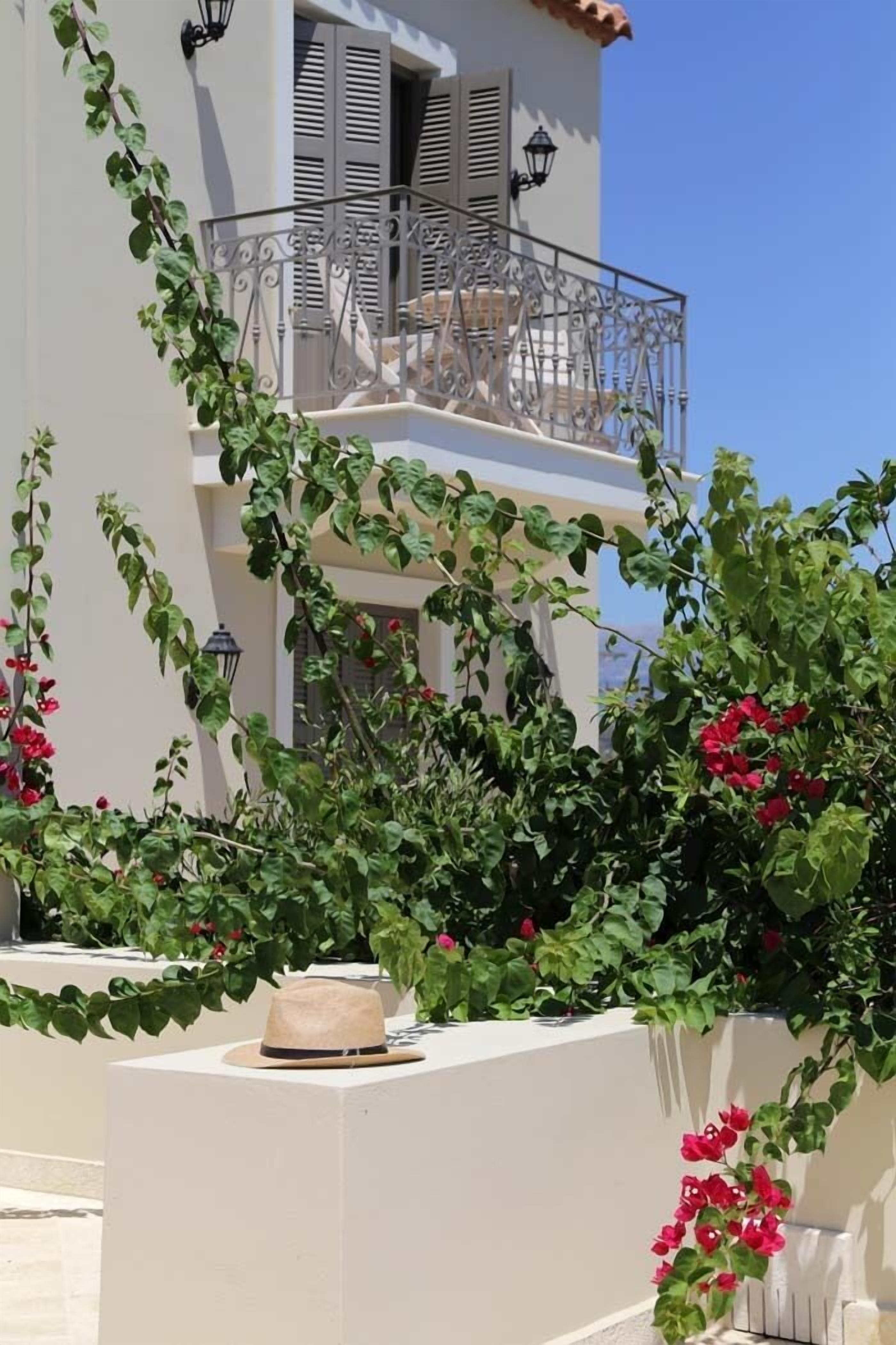 Ein Gebäude mit Balkon, weißen Wänden und roten Blumen.