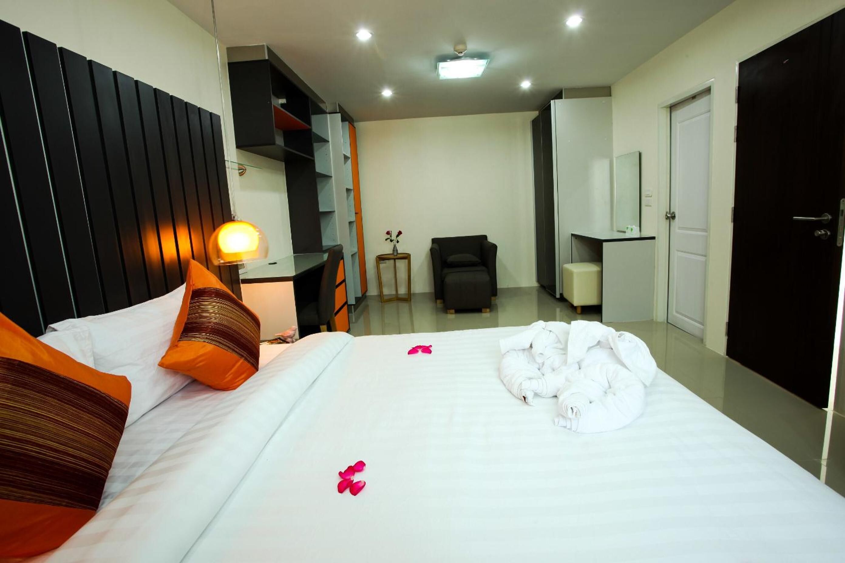 A hotel room with a bed, bedside table, lamp, and a wardrobe.