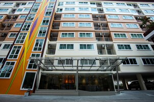 Un hotel de varios pisos con fachada moderna, ventanas amplias y un área de entrada cubierta.