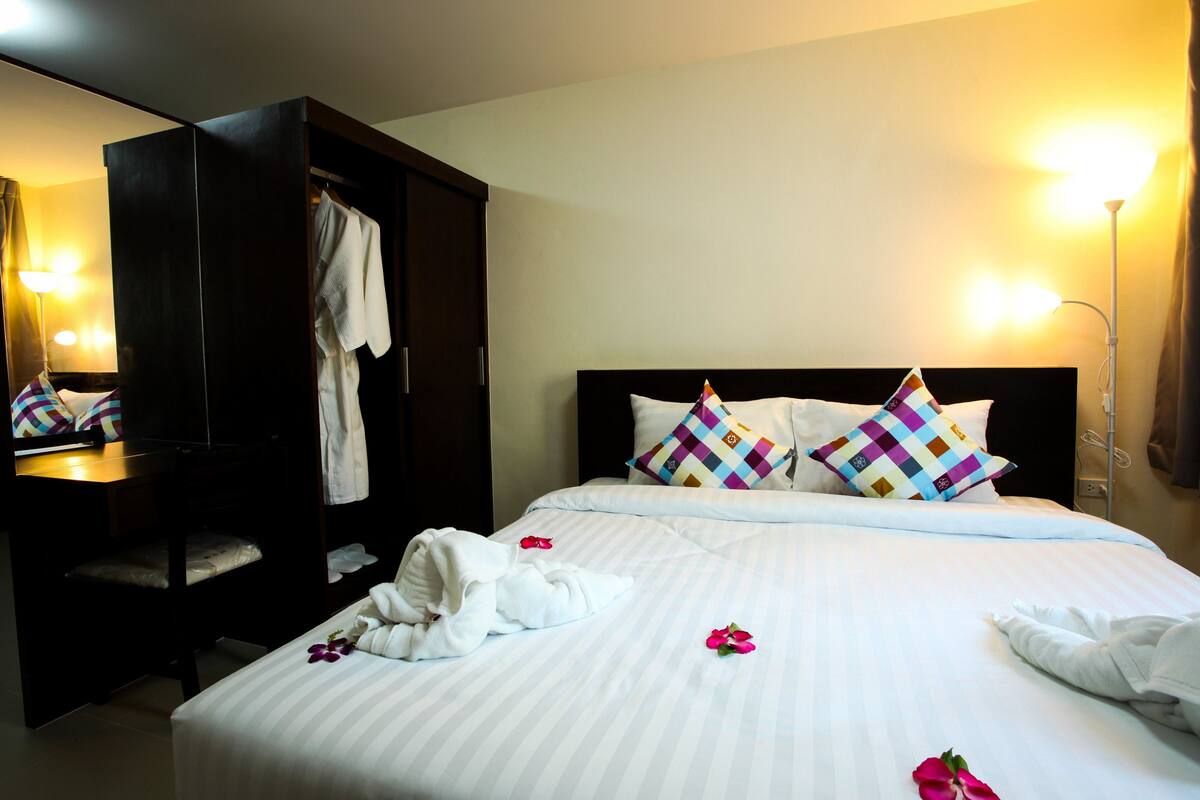 Habitación de hotel con cama, armario y espejo.
