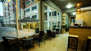 A hotel lobby with a reception desk, seating area, and large windows offering views of the building's exterior. - Patt Serviced Apartments (Chonburi)
