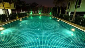 A swimming pool with a grid pattern, surrounded by a low fence and palm trees. - Patt Serviced Apartments (Chonburi)