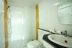 Un baño con inodoro blanco, un lavabo con espejo y zona de ducha.